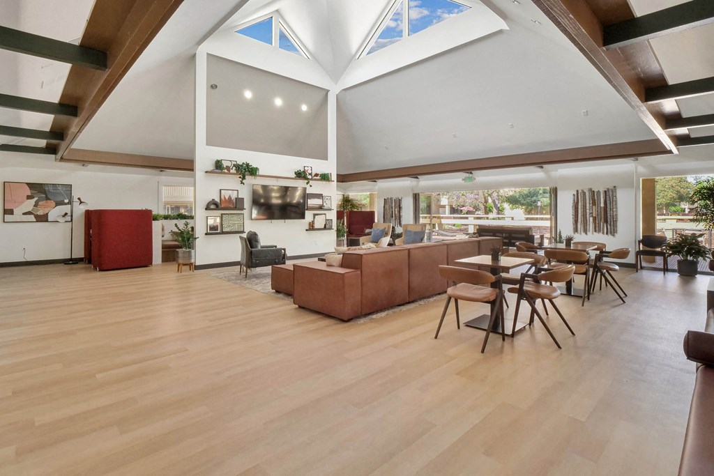 a large living room with a high ceiling and a dining room with tables and chairs at Summerwood Apartments, Santa Clara, CA 95050