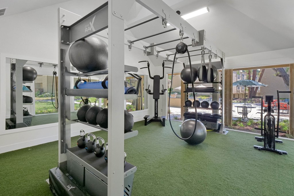 a gym with weights and other equipment on a green floor at Summerwood Apartments, Santa Clara