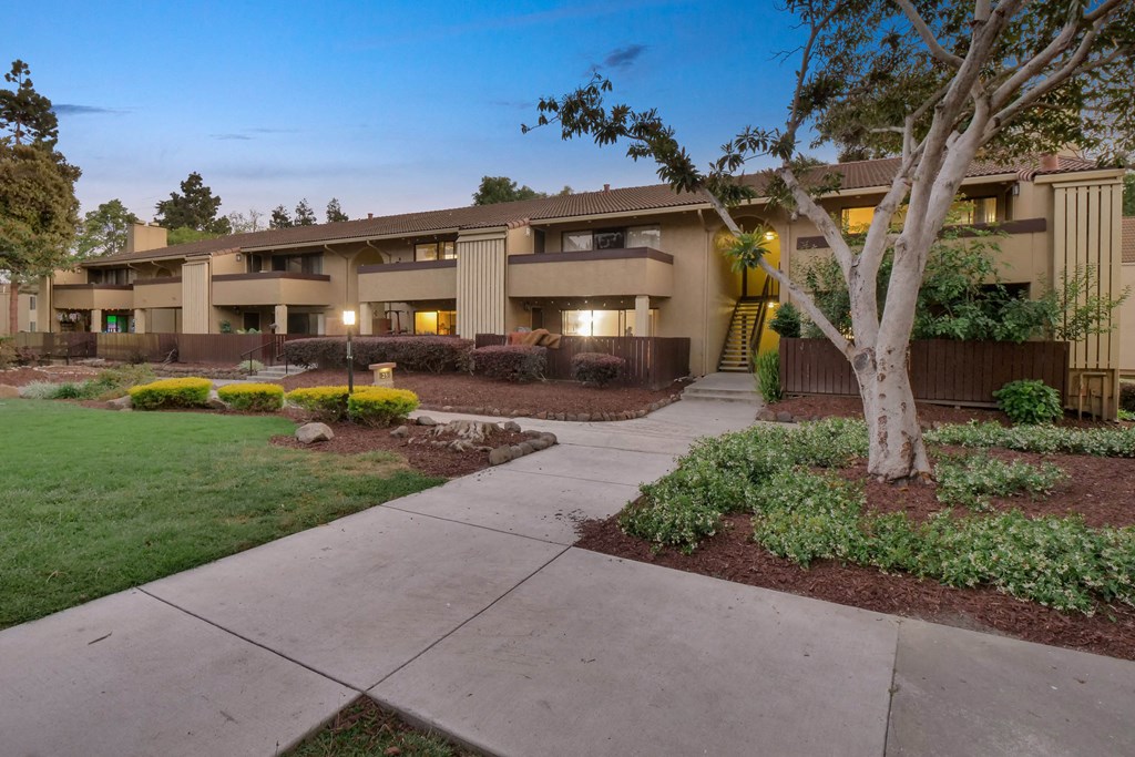 a building with a sidewalk and trees in front of it at Summerwood Apartments, Santa Clara, 95050