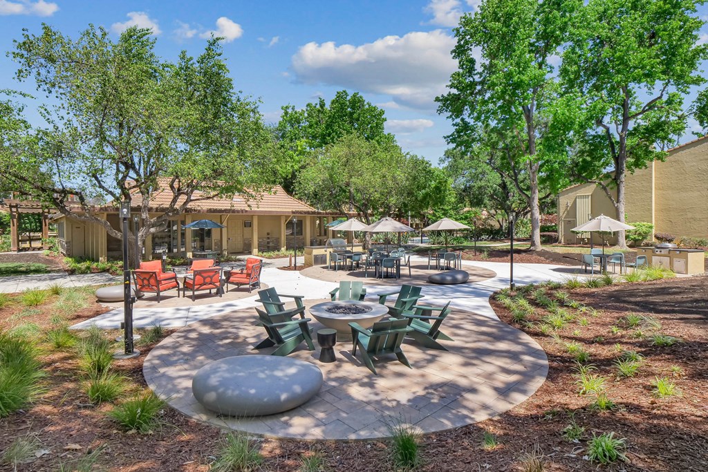 an outdoor patio with tables and chairs and trees at Summerwood Apartments, Santa Clara, 95050
