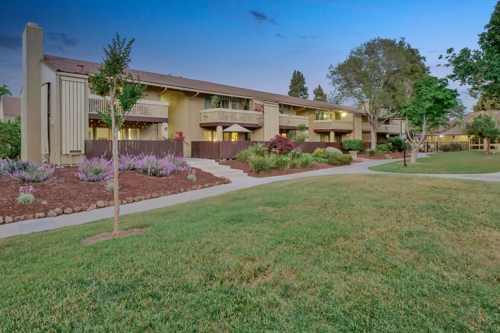 an exterior view of a house with a yard and sidewalk at Summerwood Apartments, Santa Clara