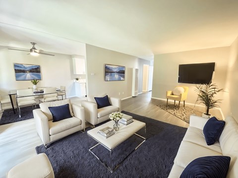 A living room with white furniture and a black flat screen TV.