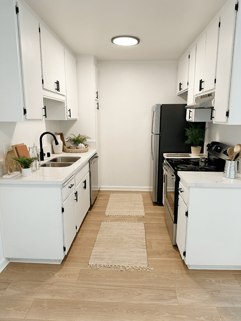 a small kitchen with white cabinets and a black stove and refrigerator