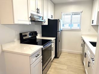 a kitchen with white cabinets and black appliances and a window