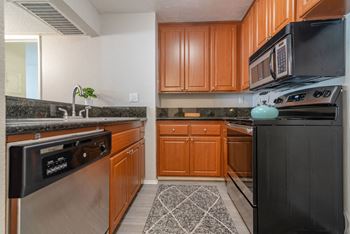 a kitchen with stainless steel appliances and wooden cabinets at City View Apartments at Warner Center, California