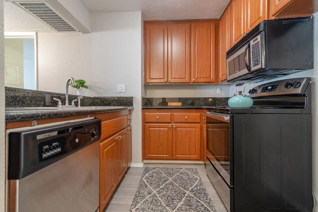 a kitchen with stainless steel appliances and wooden cabinets at City View Apartments at Warner Center, Woodland Hills California