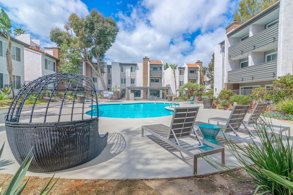 a pool with chairs and a hammock in front of an apartment building at City View Apartments at Warner Center, Woodland Hills California