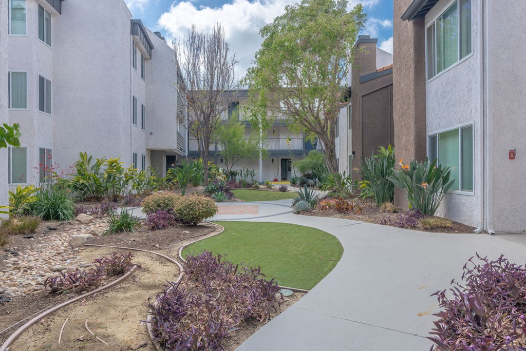 an exterior view of an apartment building with a sidewalk and grass an exterior view of an apartment building with a sidewalk and grass at City View Apartments at Warner Center, California
