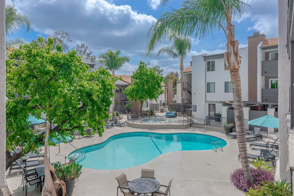 a swimming pool with tables and chairs and palm trees at City View Apartments at Warner Center, Woodland Hills, CA