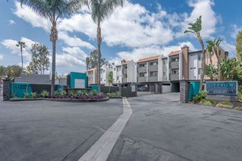 an empty parking lot in front of a building with palm trees at City View Apartments at Warner Center, Woodland Hills, CA