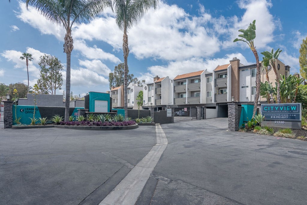 an empty parking lot in front of a building with palm trees at City View Apartments at Warner Center, California, 91367