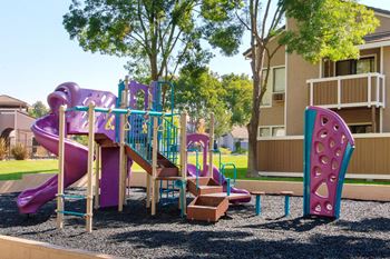 a playground with a slide and other toys in front of an apartment building at Diablo Vista, Livermore