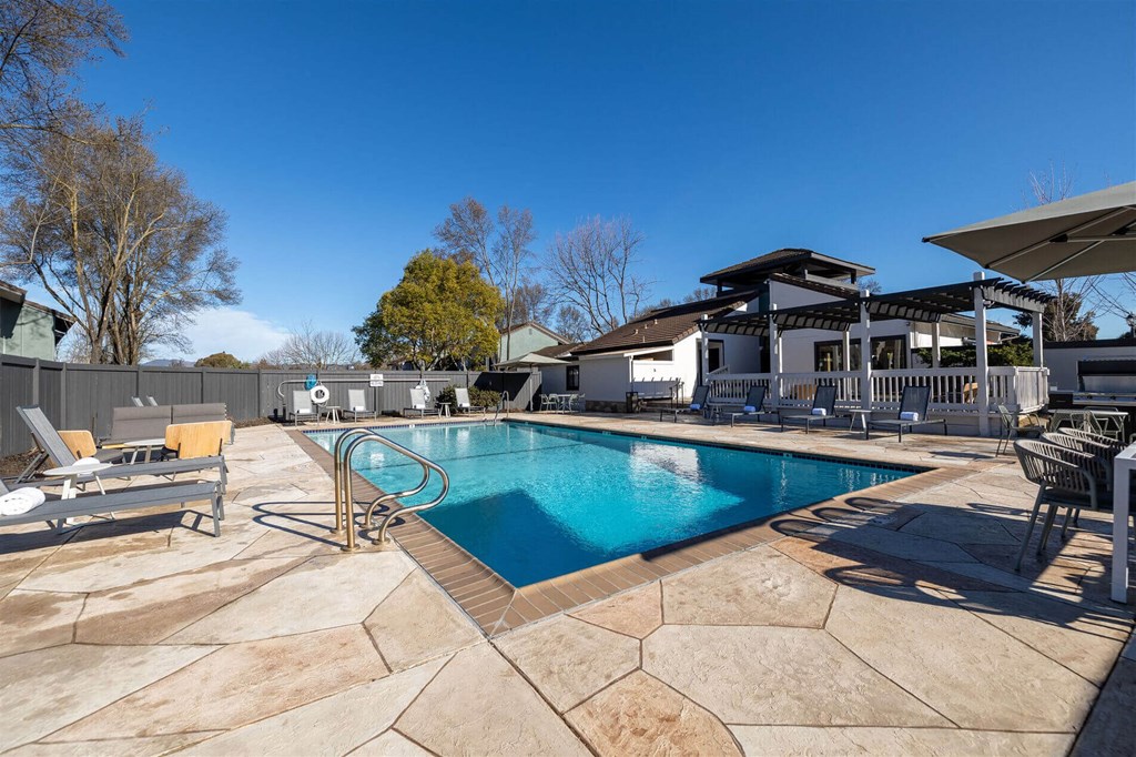 a swimming pool with chairs and umbrellas next to a house at Diablo Vista, Livermore