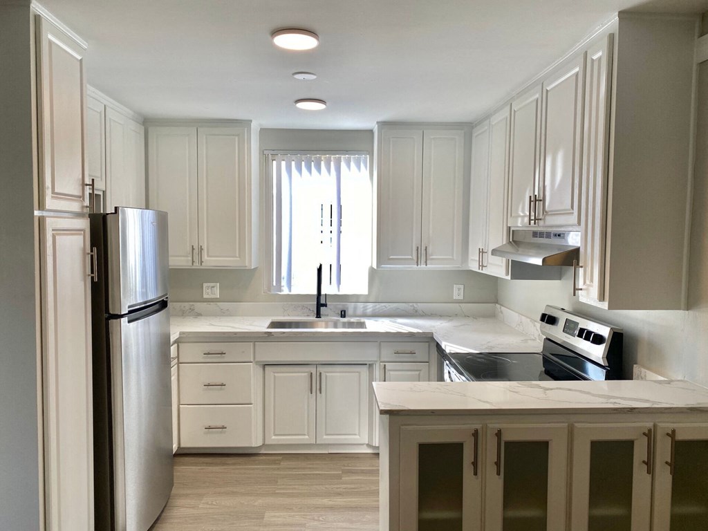 a kitchen with white cabinets and stainless steel appliances at The Flats on Addison, Sherman Oaks, 91423