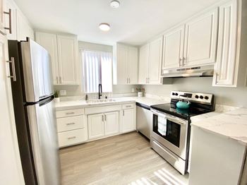 a white kitchen with stainless steel appliances and white cabinets at The Flats on Addison, California