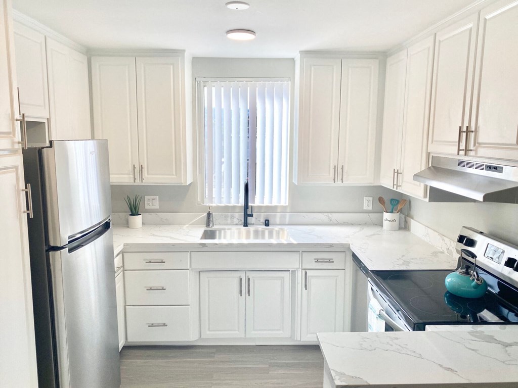 a white kitchen with stainless steel appliances and white cabinets at The Flats on Addison, California, 91423