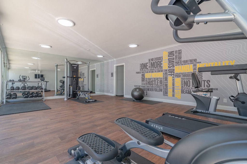 the gym is equipped with exercise machines and weights at The Flats on Addison, Sherman Oaks