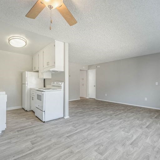 an empty living room with a kitchen and a ceiling fan at The Arches Apartments, El Cajon, CA 92021