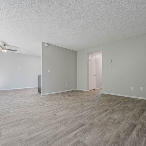 an empty living room with a hard wood floor at The Arches Apartments, California