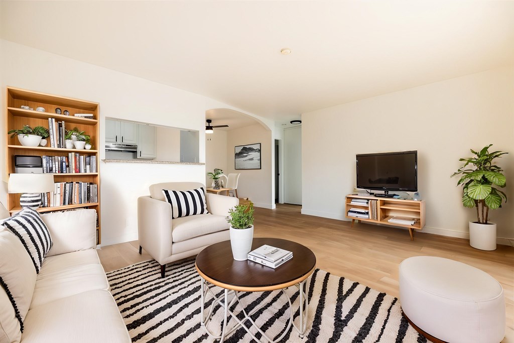 A living room with a white couch, a coffee table, and a television.