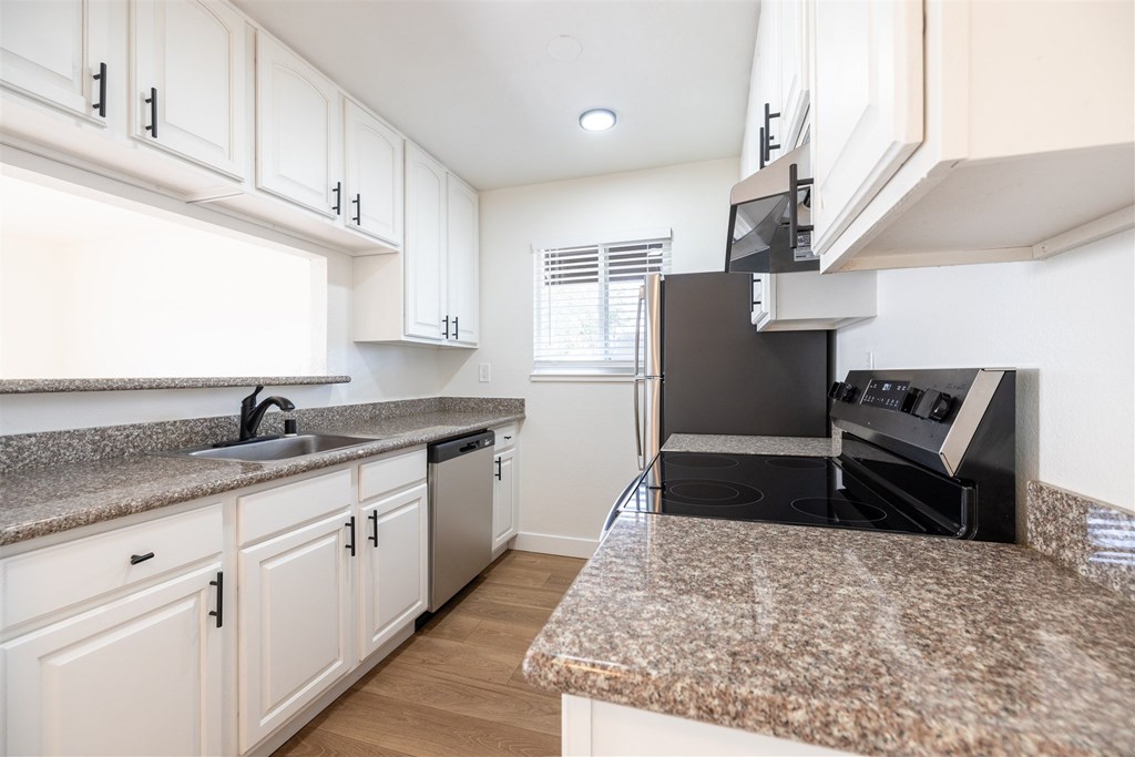 A kitchen with granite countertops and white cabinets.at Summerhill Place Apartments, California