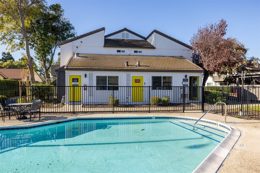 A white house with a pool in front.