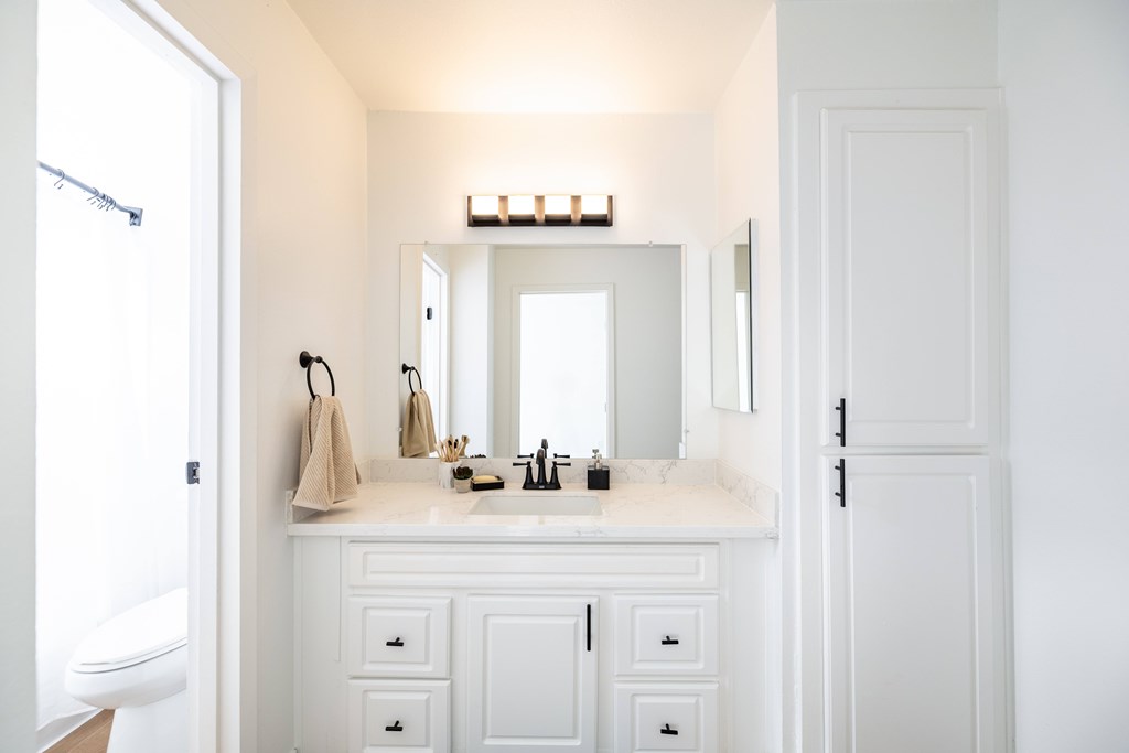 White bathroom with a mirror and storage at Sunnyvale Crossings Apartments, Sunnyvale, CA, California