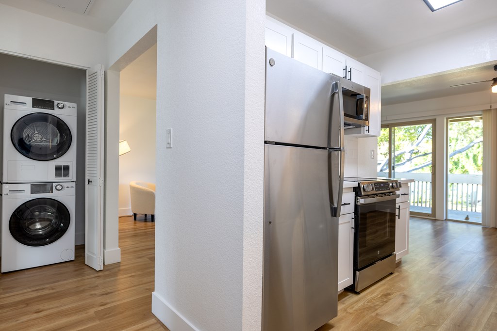 A white refrigerator is in a kitchen next to a washer and dryer at Summerwood Apartment , Santa Clara, CA