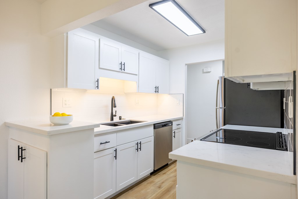A kitchen with white cabinets and a black fridge at Summerwood Apartment , Santa Clara