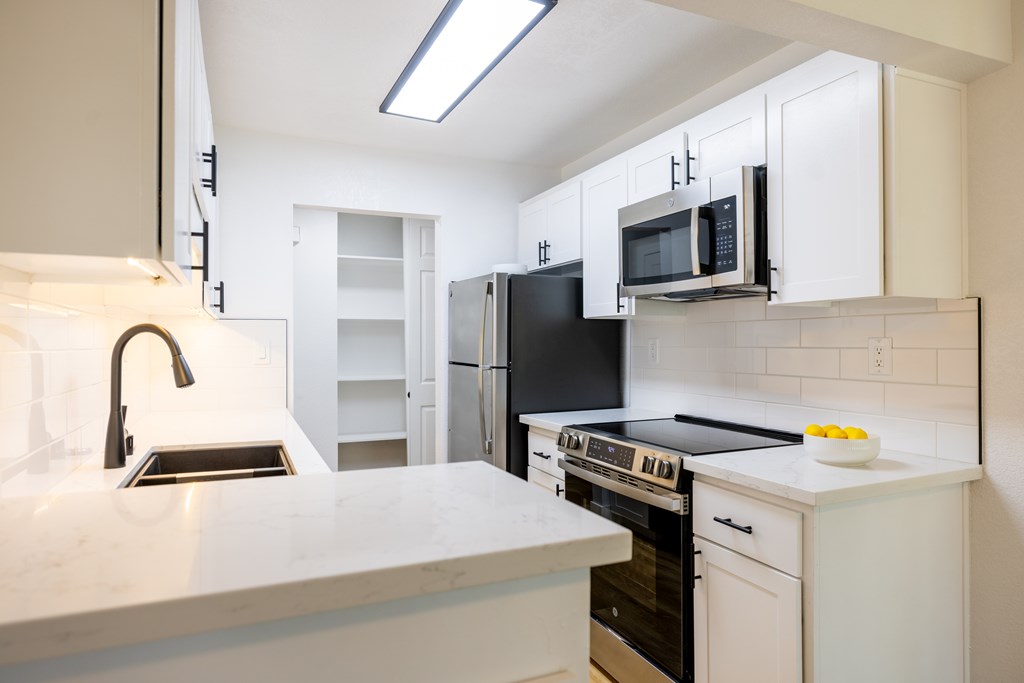 A kitchen with white cabinets and black appliances at Summerwood Apartment , California, 95050