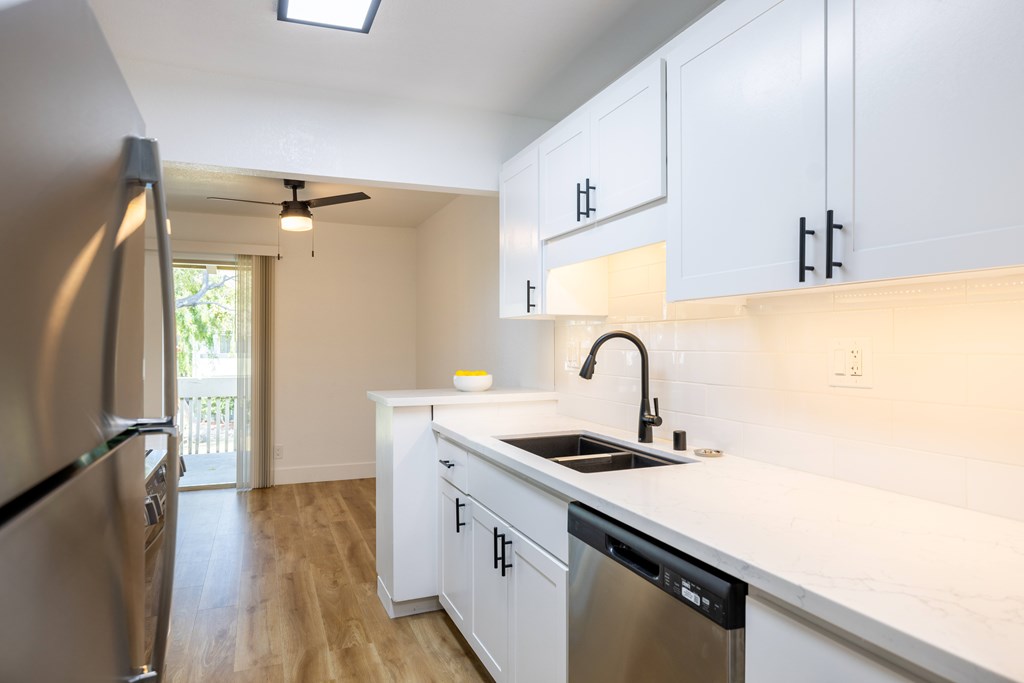 A kitchen with white cabinets and a stainless steel dishwasher at Summerwood Apartment , Santa Clara, California