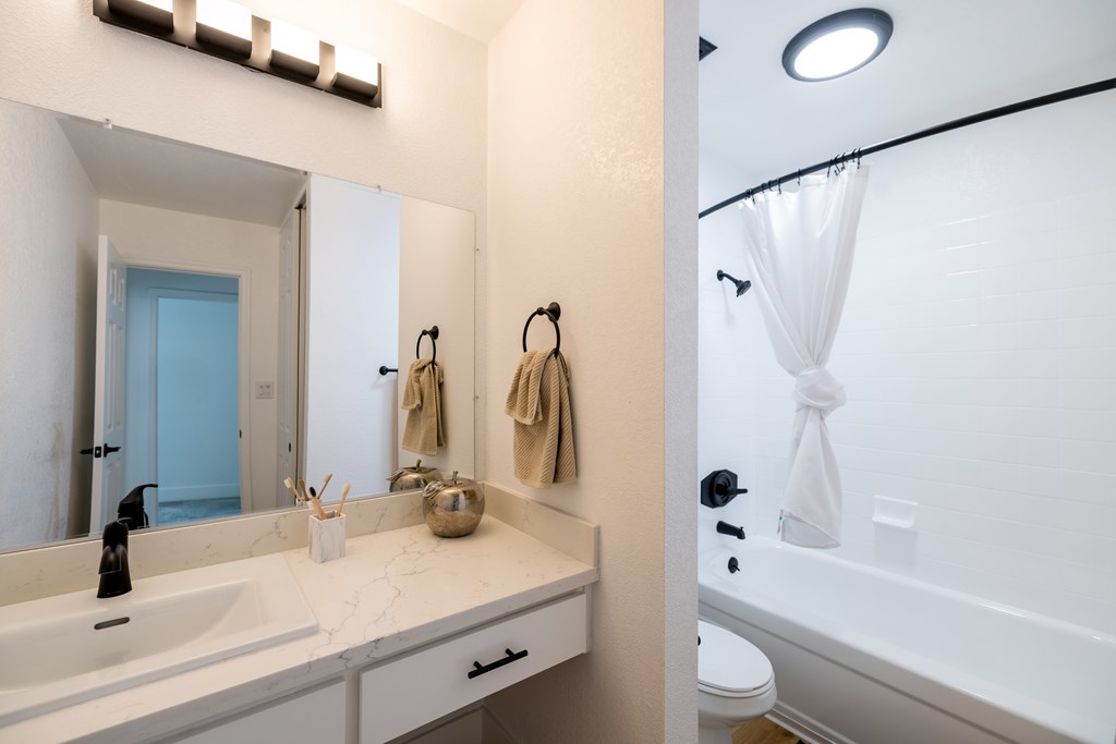 A bathroom with a white sink and a white bathtub at Summerwood Apartment , Santa Clara, CA