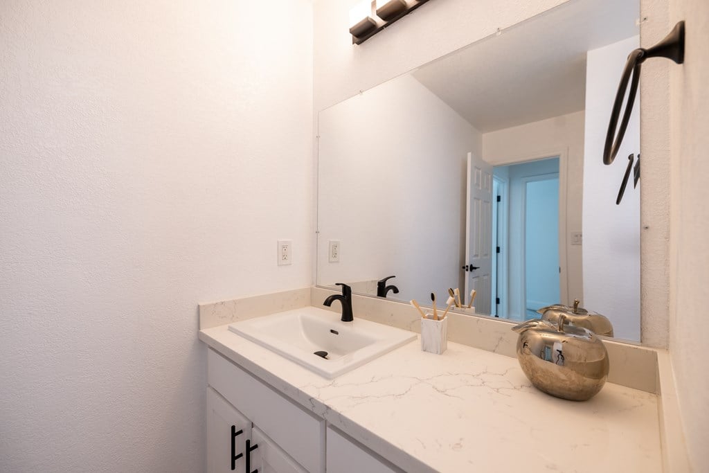 A bathroom with a white sink and a mirror at Summerwood Apartment , Santa Clara, California