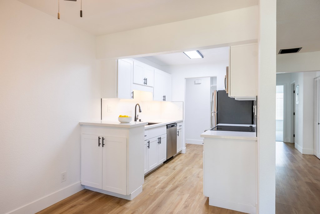 A kitchen with white cabinets and a wooden floor at Summerwood Apartment , California