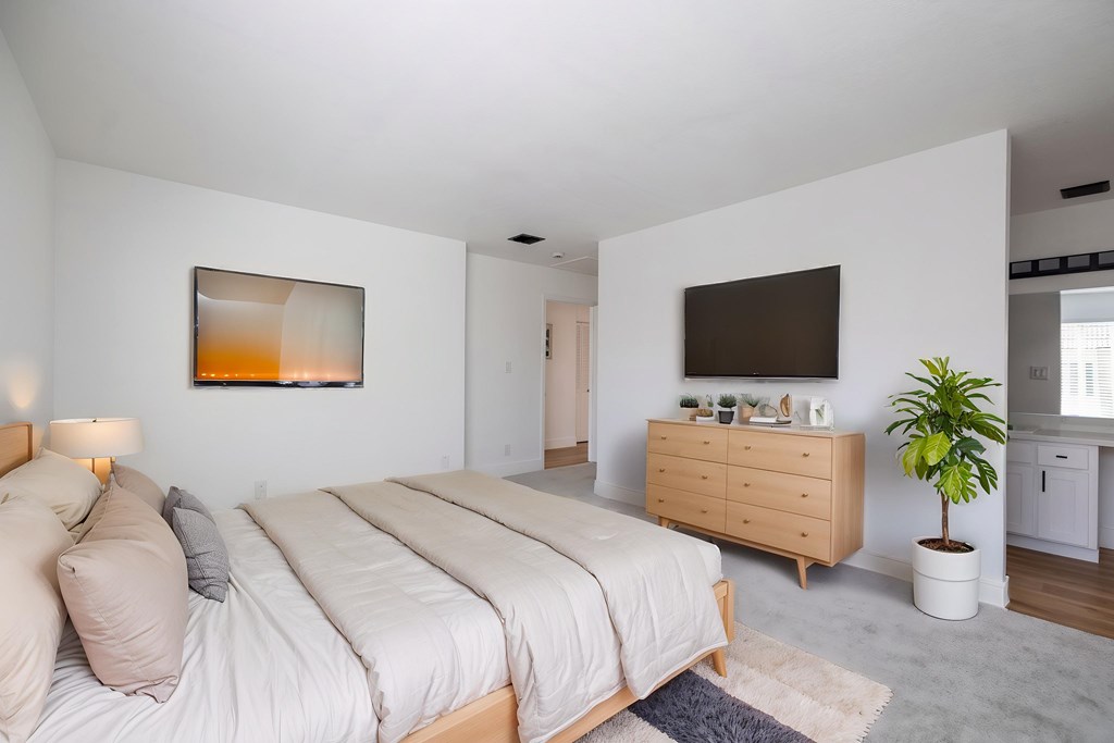 A bedroom with a large bed, a dresser, and a plant at Summerwood Apartment, Santa Clara, CA, 95050