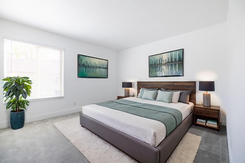 A bedroom with a large bed and two pictures on the wall.