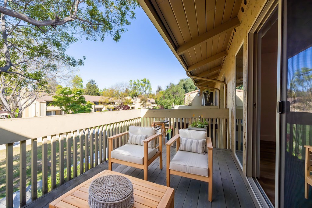 A wooden balcony with two chairs and a table at Summerwood Apartment , Santa Clara, CA