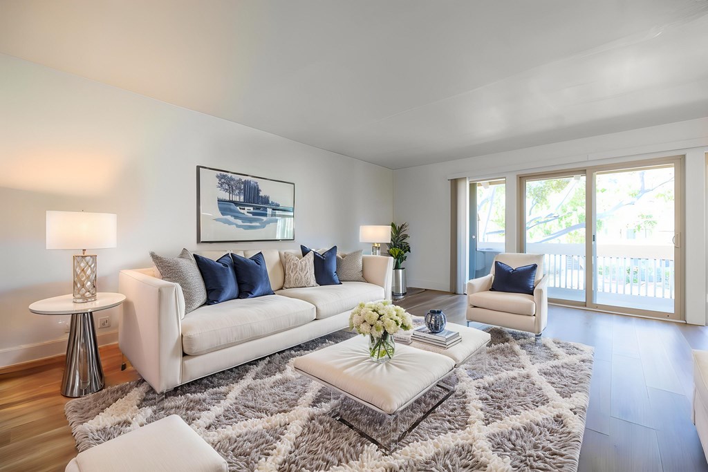 A living room with a white couch, a coffee table, and a painting on the wall at Summerwood Apartment , Santa Clara, 95050
