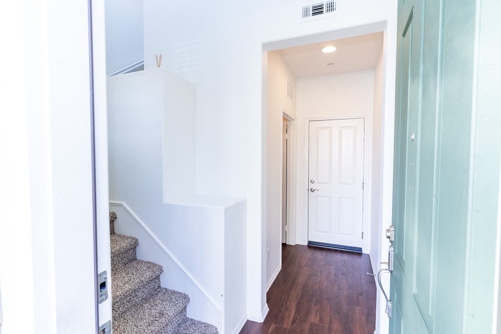 a view of the hallway of a home with stairs and a white door at The Vines at Riverpark, LLC, California, 93036