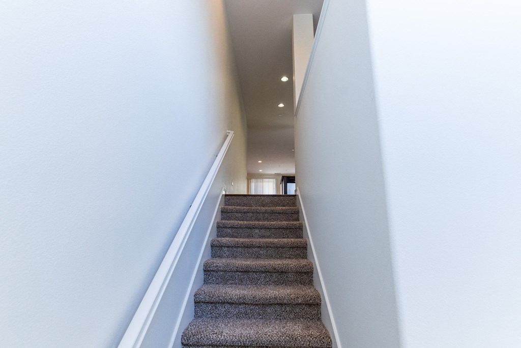 a view down the stairs of a hallway with carpeted stairs and white walls at The Vines at Riverpark, LLC, California, 93036