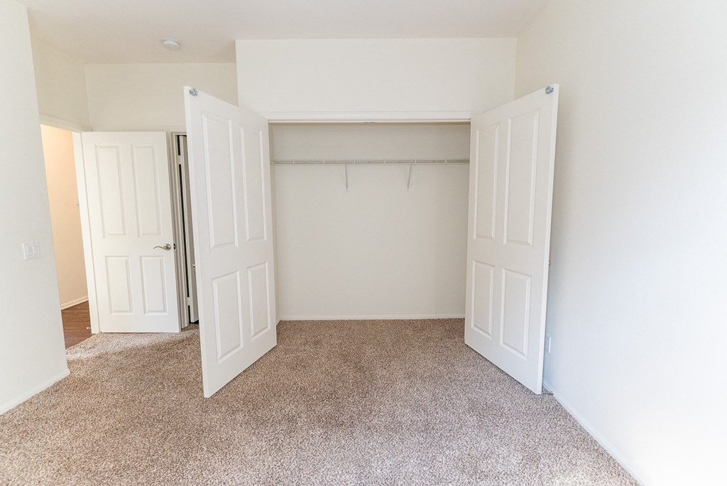 an empty bedroom with two doors leading to a walkin closet and a carpeted floor at The Vines at Riverpark, LLC, California, 93036