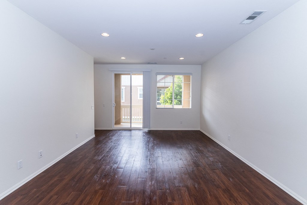 an empty living room with white walls and wood floors at The Vines at Riverpark, LLC, California, 93036