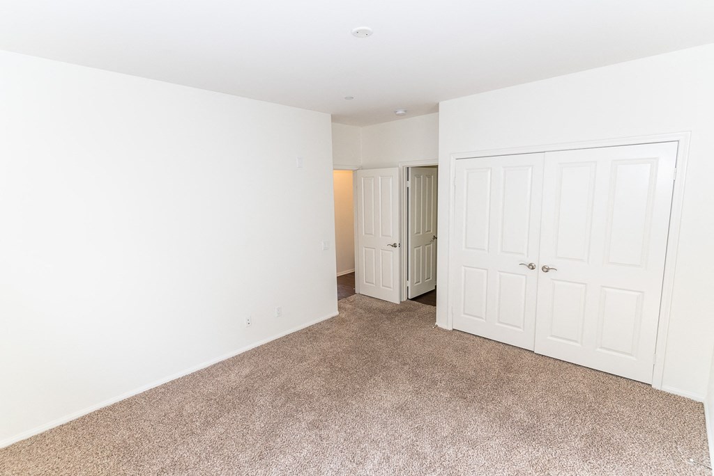 a bedroom with white walls and carpet and a closet at The Vines at Riverpark, LLC, California, 93036