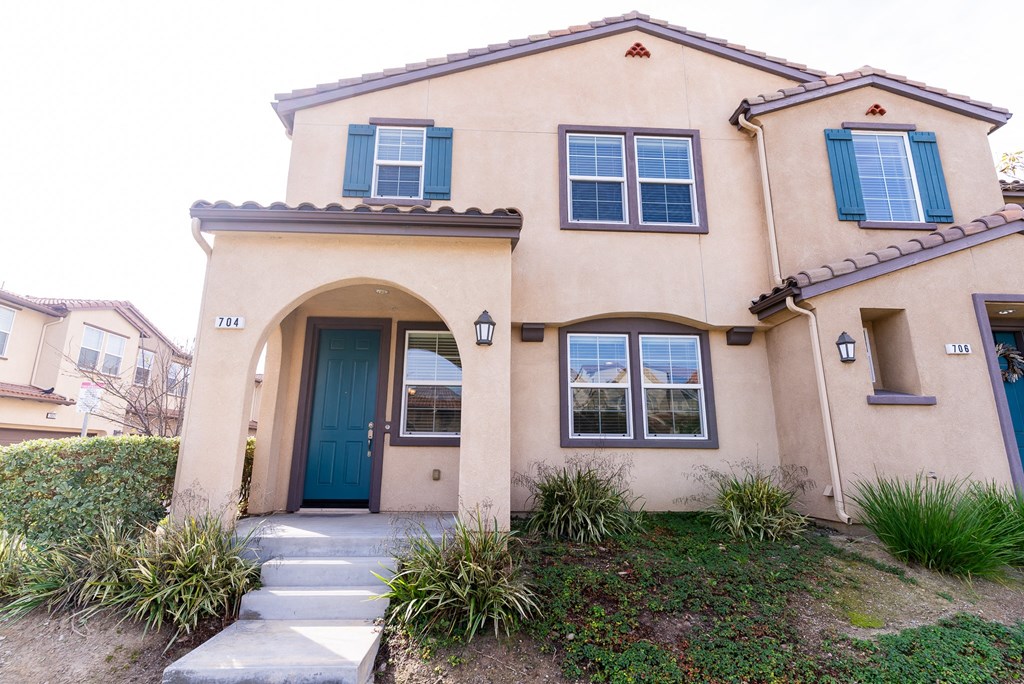 the front of a two story apartment with a blue door at The Vines at Riverpark, LLC, California, 93036