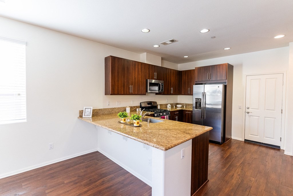 a kitchen with a granite counter top and a stainless steel refrigerator at The Vines at Riverpark, LLC, California, 93036