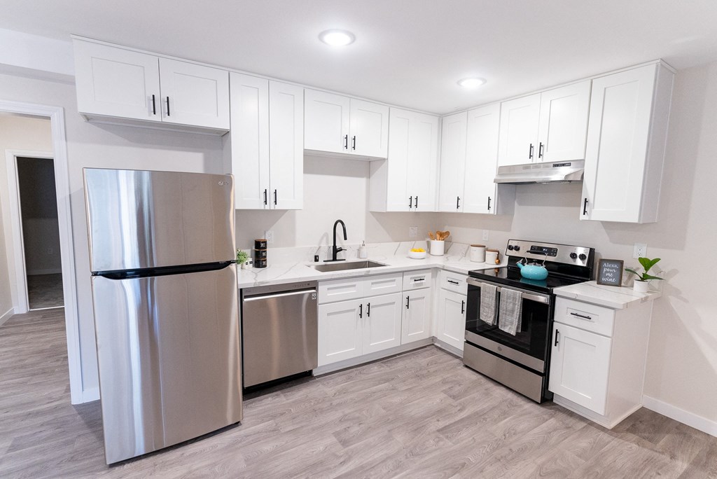 a white kitchen with stainless steel appliances and white cabinets at The Flats on Addison, Sherman Oaks, CA 91423
