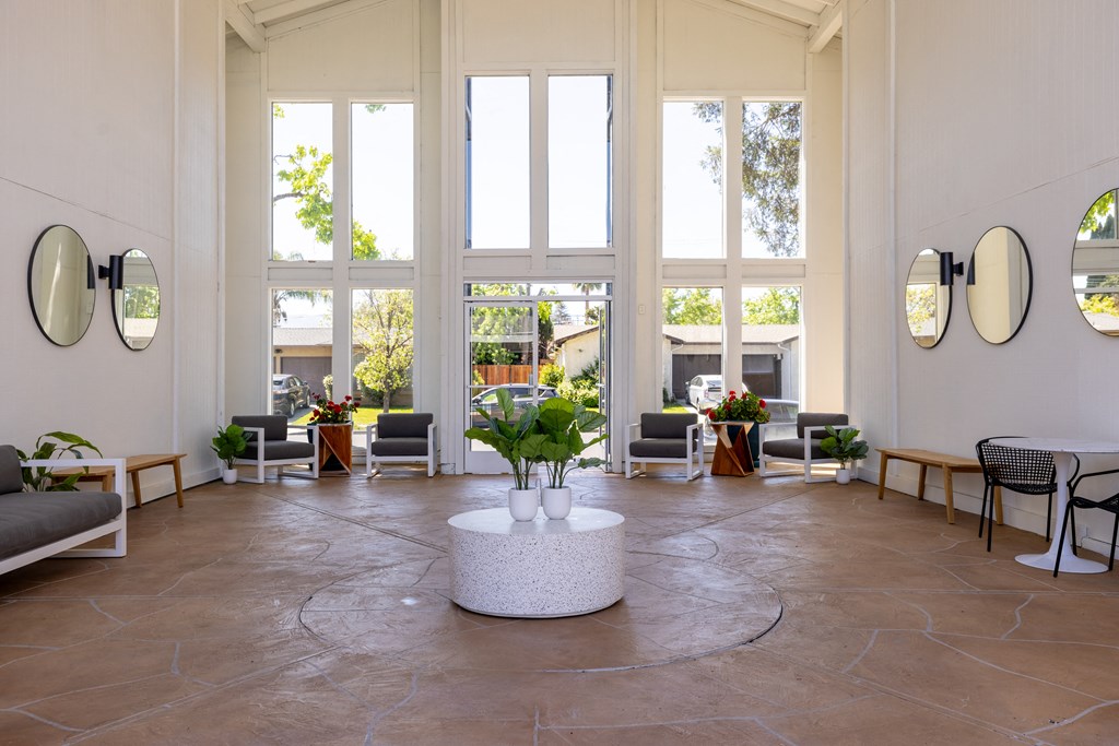 a living room with large windows and a table with plants at Campbell West Apartments, Campbell, CA