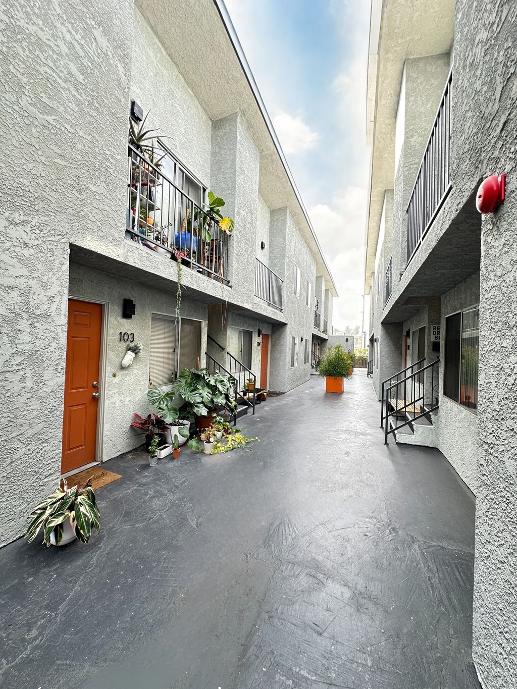 a courtyard between two buildings with potted plants at The Marq Apartments LLC, California, 90042