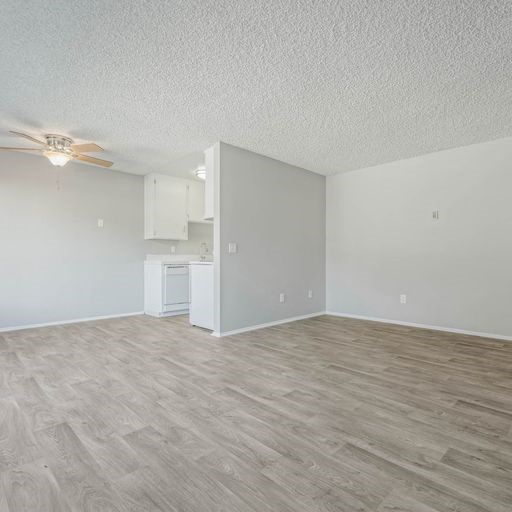 an empty living room and kitchen with a ceiling fan at The Arches Apartments, El Cajon, CA 92021