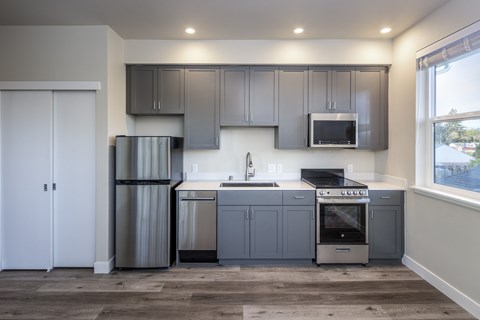 A modern kitchen with stainless steel appliances and grey cabinets.at 888 Fourth Street Apartments, LLC, Santa Rosa California